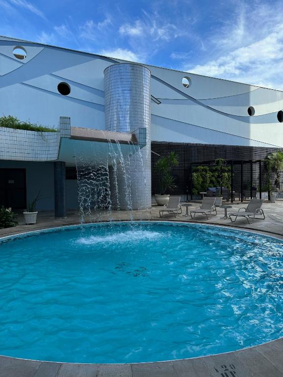 a swimming pool with a fountain in front of a building at Hotel Saint Paul in Sao Jose do Rio Preto