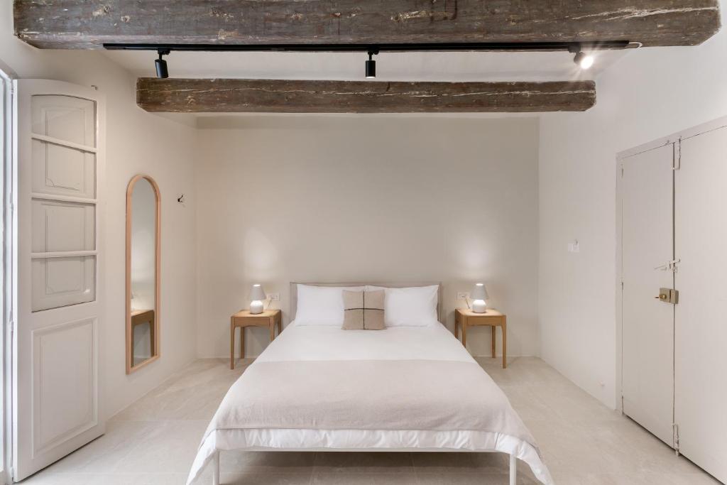 a white bedroom with a bed and two tables at Historic Apartments - SUPER location near Valletta Ferry in Cospicua
