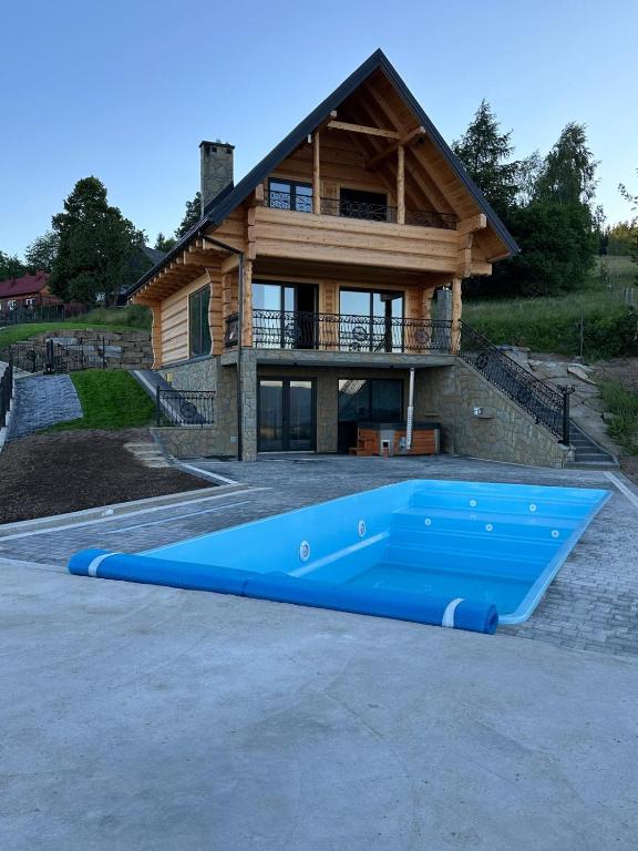 a large blue swimming pool in front of a house at Dom Na Brzegu in Limanowa