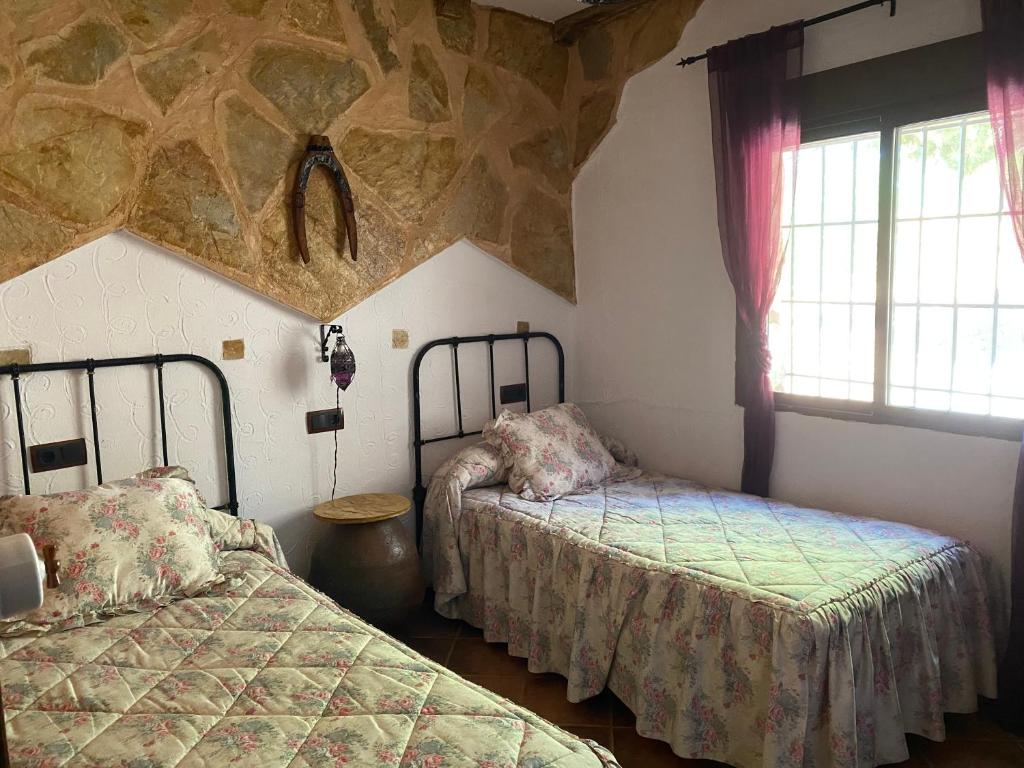 une chambre avec deux lits et un mur en pierre dans l'établissement Casa Rural Balcón De San Roque, à Valverde de Júcar