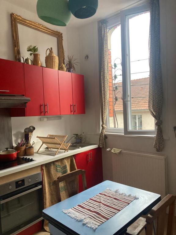 une cuisine avec des placards rouges, une table et une fenêtre dans l'établissement Appartement de charme, à Lille