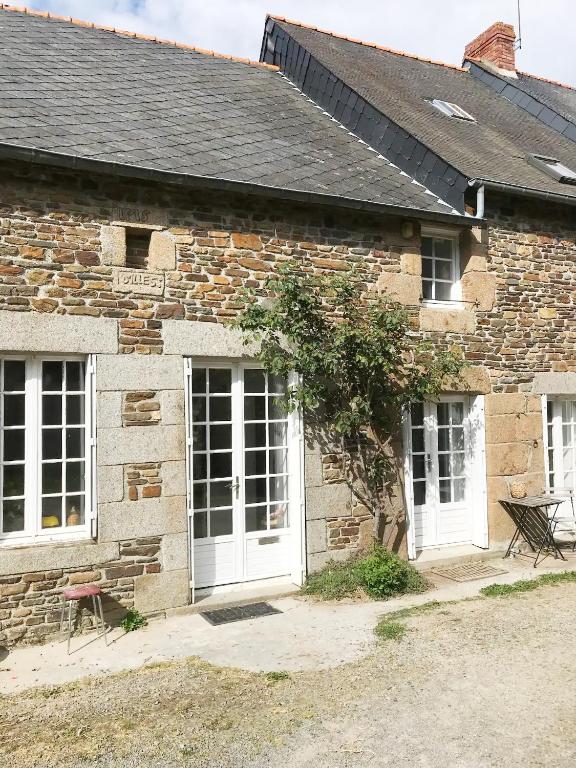 - un vieux bâtiment en pierre avec des portes et des fenêtres blanches dans l'établissement Maison de Charles, à Sougéal
