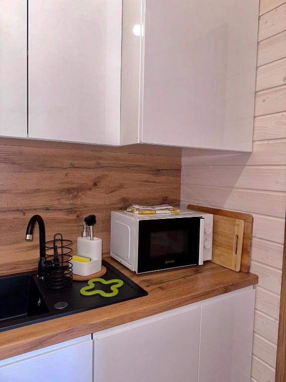 Compact kitchen area with microwave, sink, and wooden countertop.