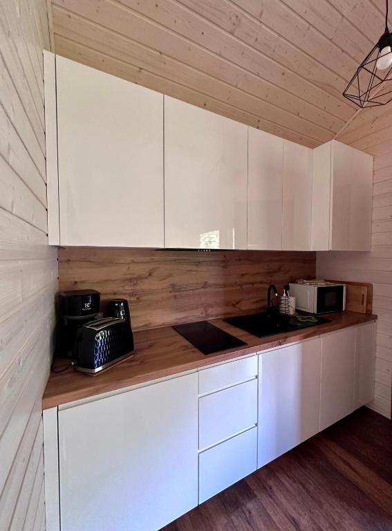 Modern kitchen with white cabinets and wooden countertop.
