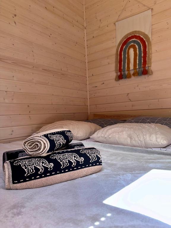 Bed with folded towels and rainbow wall hanging.