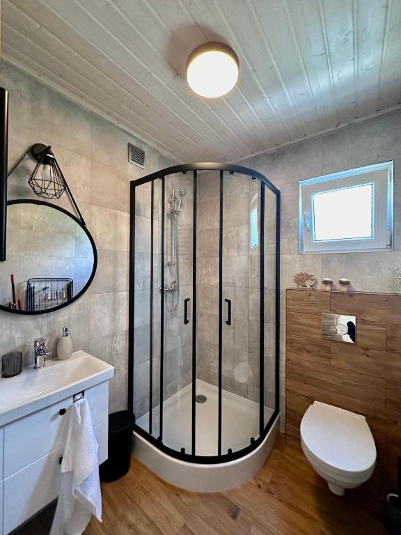 Bathroom with glass shower, round mirror, and wooden accents.