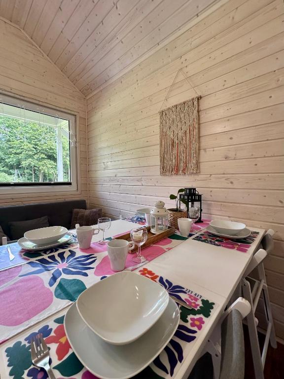 Dining table set with plates and cups, colorful tablecloth, and wooden walls.