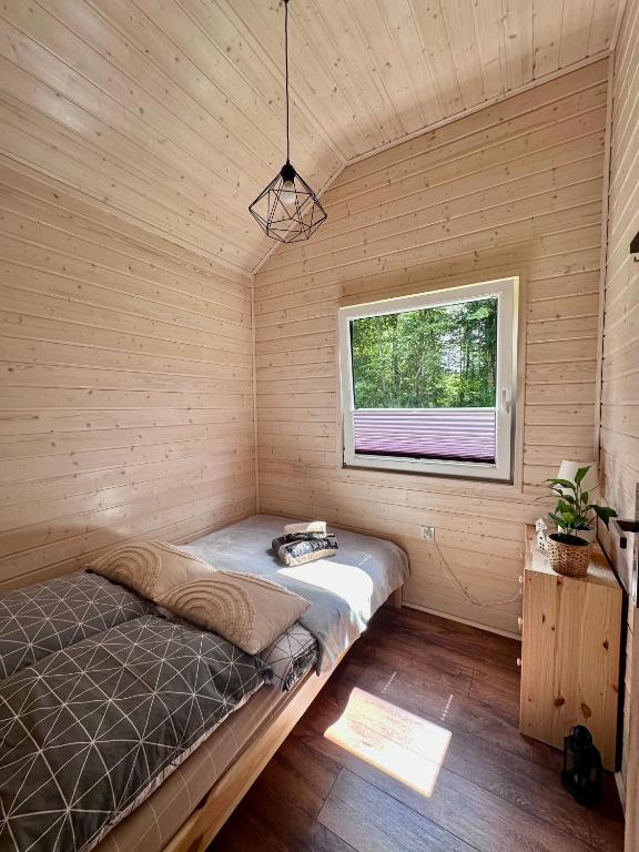 Small bedroom with wooden walls, single bed, and window view of trees.
