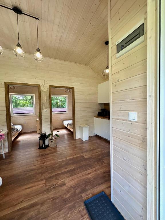 Interior view of cabin with two bedrooms, wooden floors, and hanging lights.