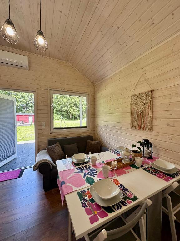 Dining area in wooden cabin with table set for four, overlooking garden.