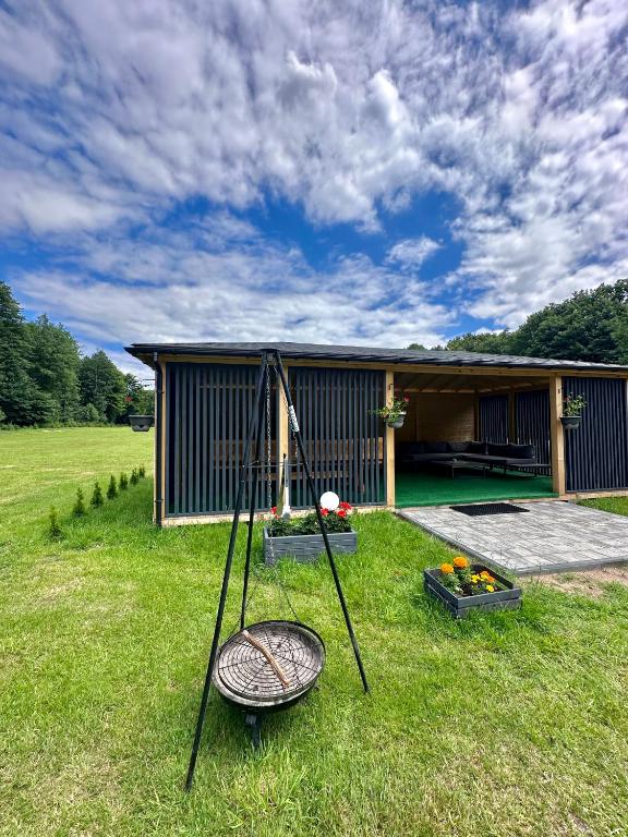 Outdoor cabin with fire pit and flower boxes, set in a grassy field.