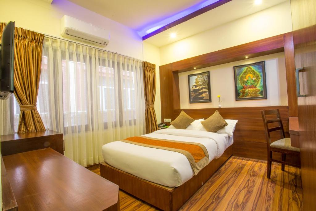 a hotel room with a large bed and a desk at Aryatara Kathmandu Hotel in Kathmandu