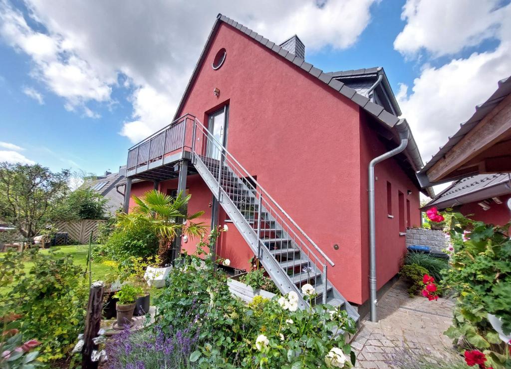 ein rotes Haus mit einer Treppe in einem Garten in der Unterkunft Backstage Apartment Kiel-Holtenau in Kiel