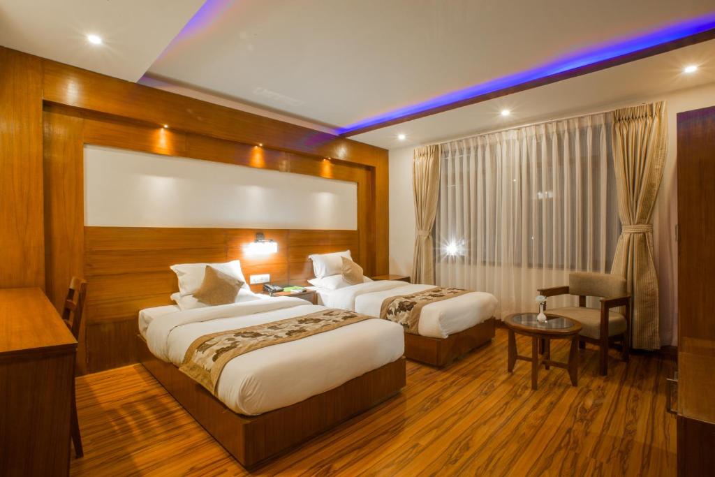 a hotel room with two beds and a table and a chair at Aryatara Kathmandu Hotel in Kathmandu