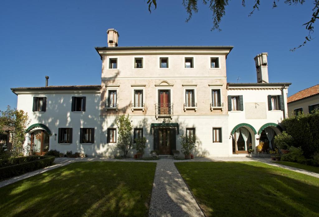 an exterior view of a large white house with a yard at Dimora di Campagna in Casale sul Sile