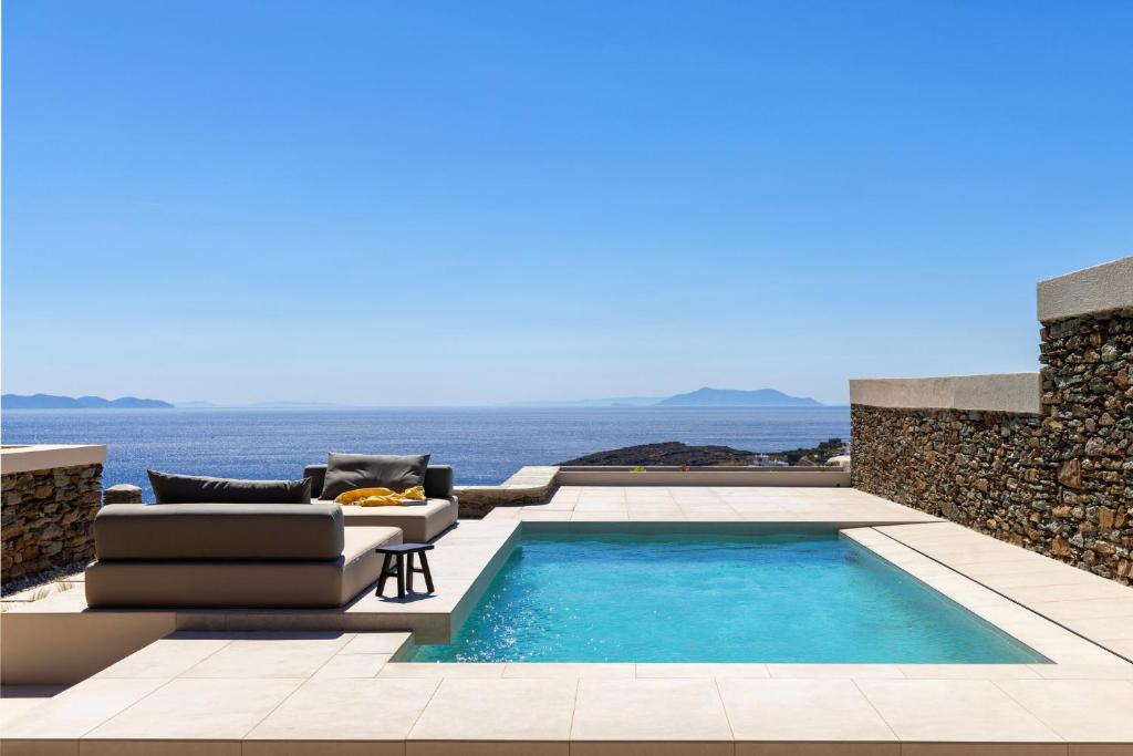 a villa with a swimming pool with a couch and a chair at casa eterna in Agios Romanos