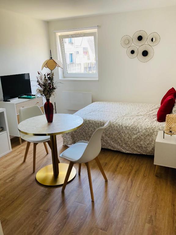 une chambre avec un lit, une table et des chaises dans l'établissement Studio Cosy en centre-ville, à Saint-Brieuc