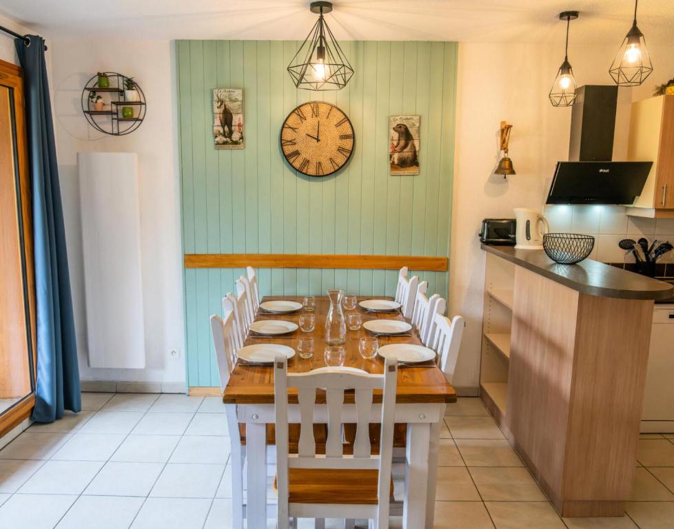 une salle à manger avec une table et une horloge au mur dans l'établissement Résidence Le Balcon Des Airelles - Joli appartement redécoré en face des pistes MAE-0774, aux Orres