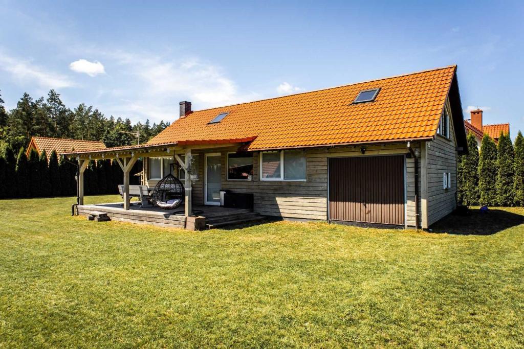a small house with an orange roof on a yard at ARKANA Rydzewo in Rydzewo