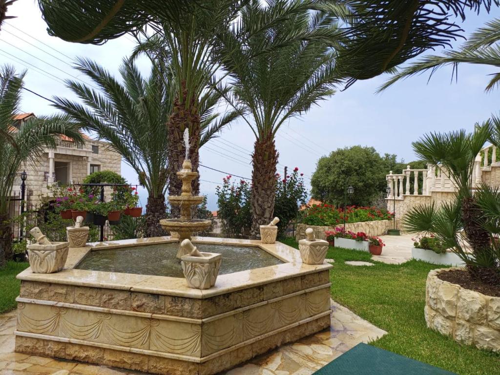 Chateau Nassar : نافورة محاطة بأشجار النخيل في فناء
