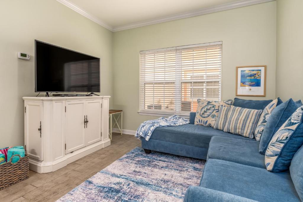 Una sala de estar con un sofá azul y un televisor de pantalla plana. en Dauphin Island Beach Club 106B, en Dauphin Island