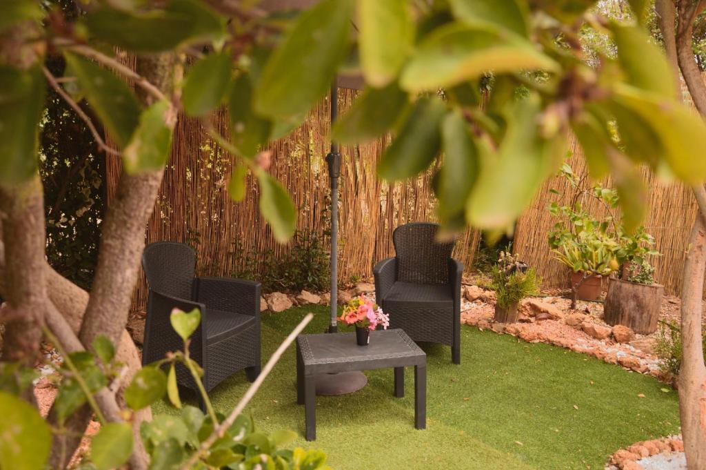 three chairs and a table in a yard with a fence at Spiaggia LazzarettoHouse in Alghero