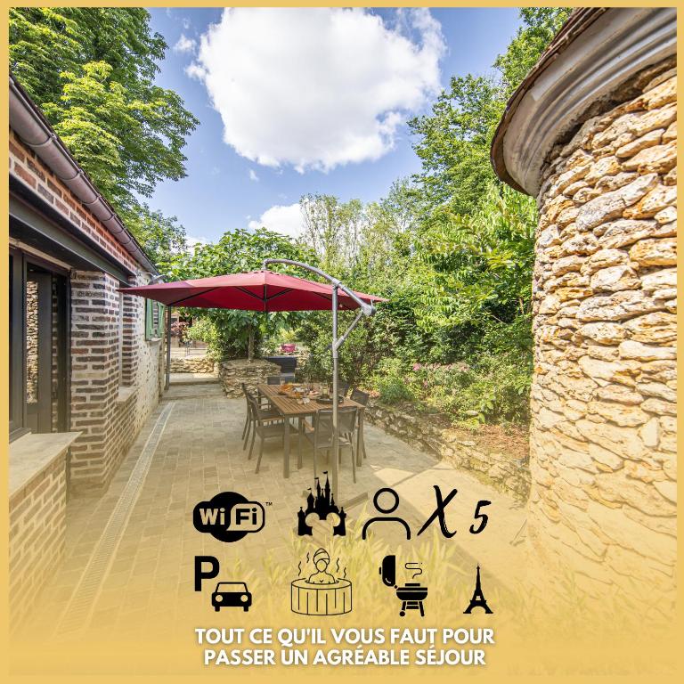 un patio avec une table et un parasol dans l'établissement Le Ru De Biche - 20min Disney - SPA du 01 05 au 01 11 - paisible, à Guérard