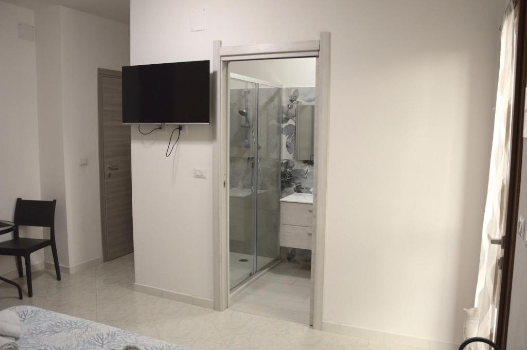 a bathroom with a shower and a television on a wall at Spiaggia LazzarettoHouse in Alghero