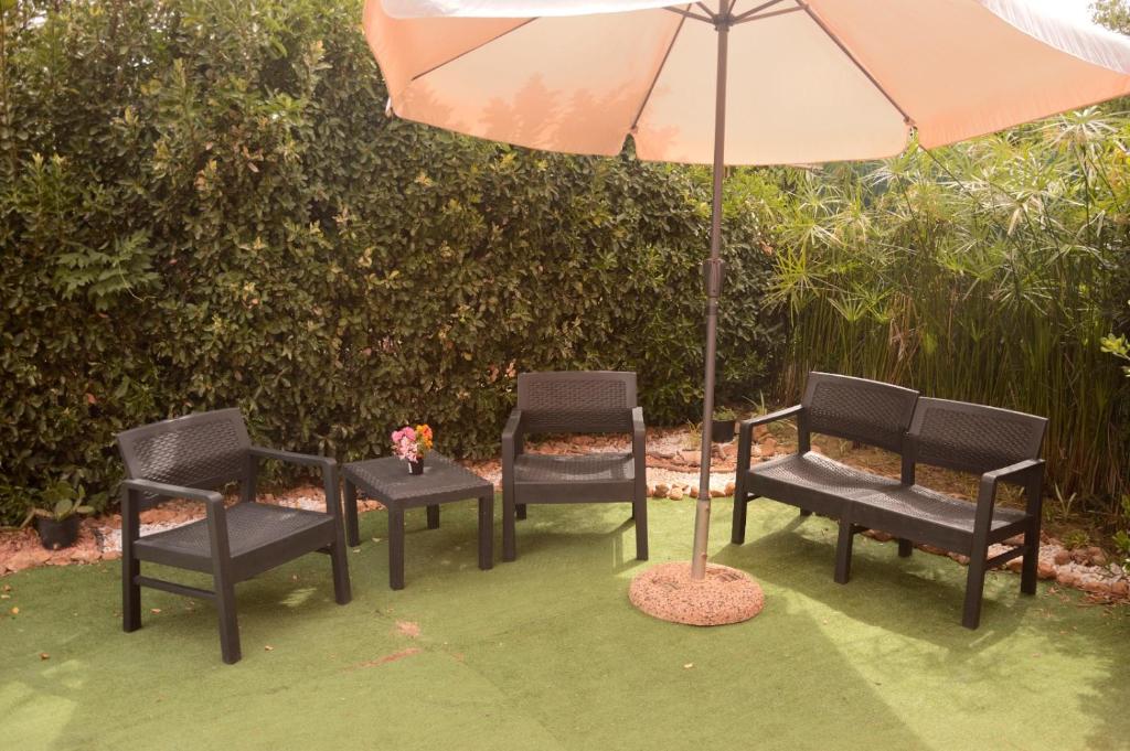 three chairs and a table with an umbrella at Spiaggia LazzarettoHouse in Alghero