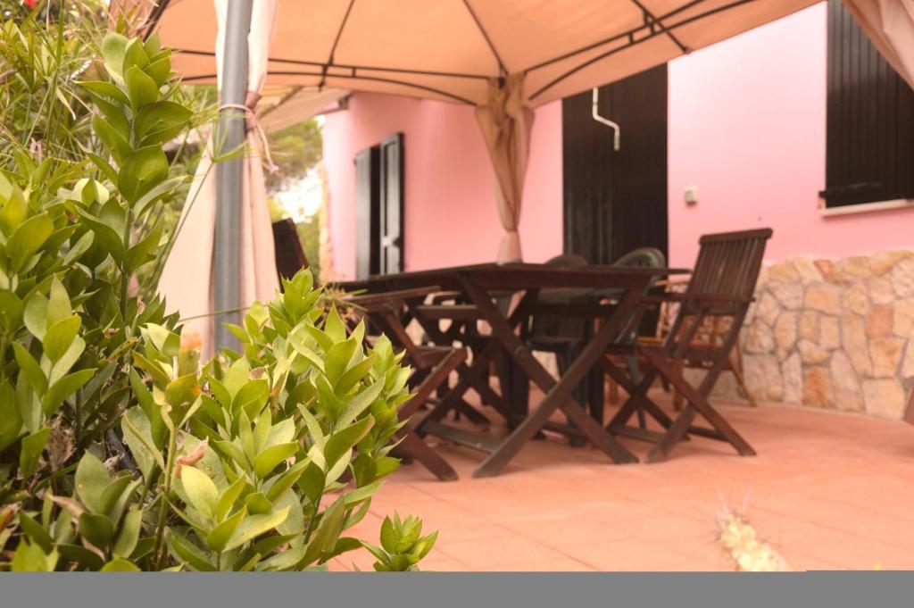 a wooden table and chairs under an umbrella on a patio at Spiaggia LazzarettoHouse in Alghero