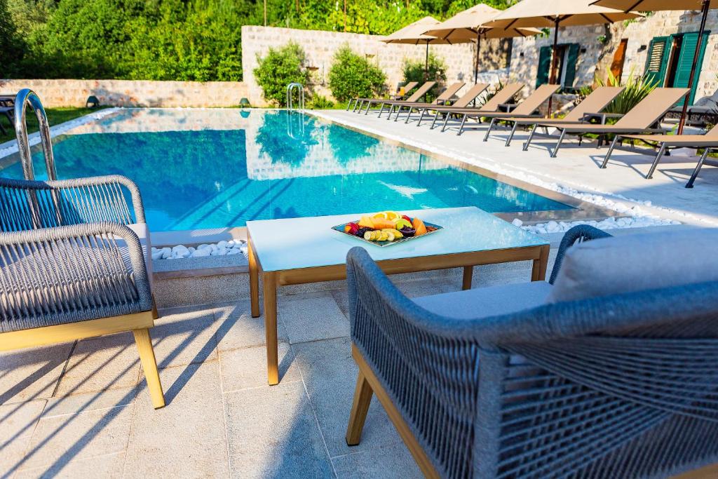 a table and chairs next to a swimming pool at Boutique hotel Ruzmarin SPA & Garden by Aycon in Budva