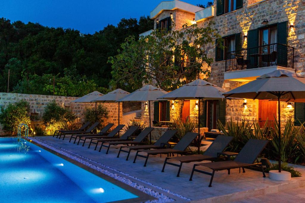a pool with chairs and umbrellas next to a building at Boutique hotel Ruzmarin SPA & Garden by Aycon in Budva