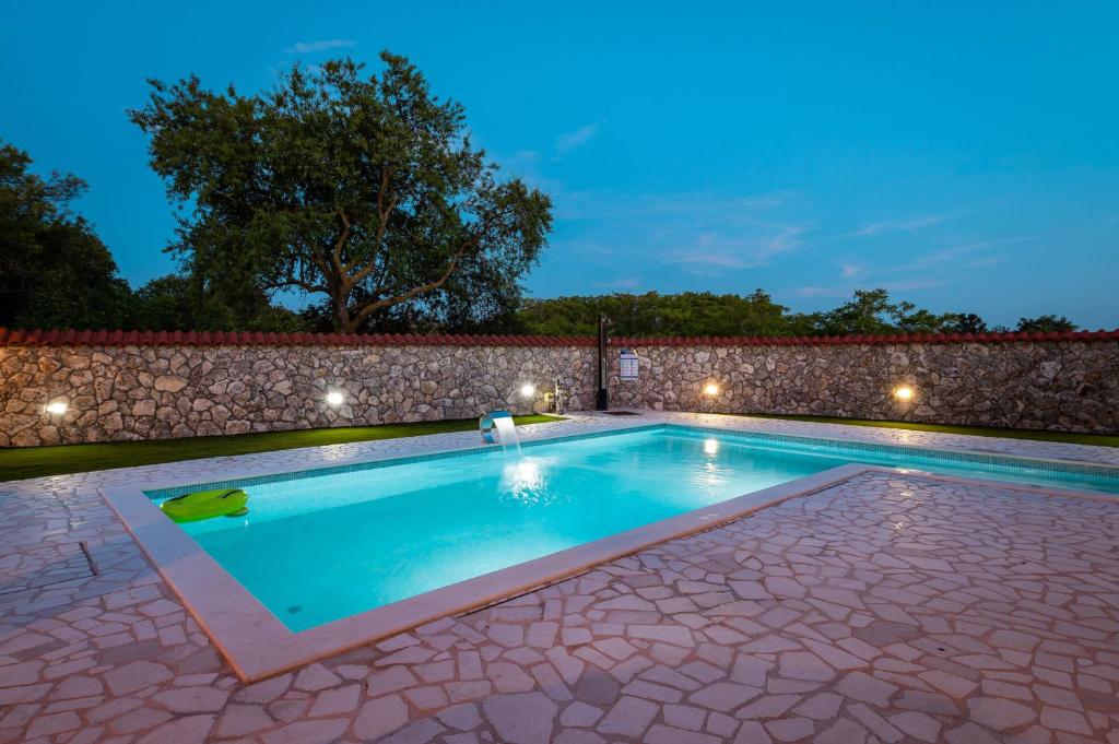 a swimming pool in a backyard with a stone wall at Villa Nika in Konjevrate