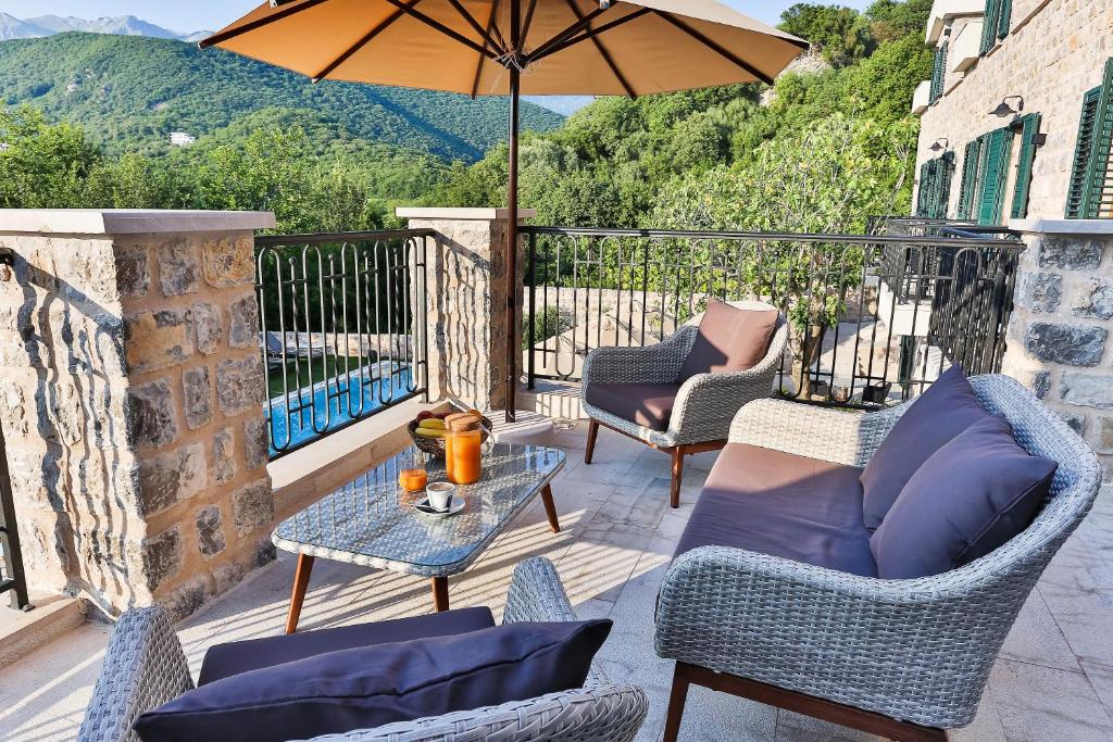 a patio with chairs and a table and an umbrella at Boutique hotel Ruzmarin SPA & Garden by Aycon in Budva