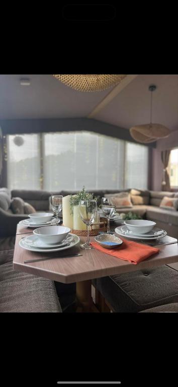 a table with plates and wine glasses on it at Cornwall caravan in Crantock