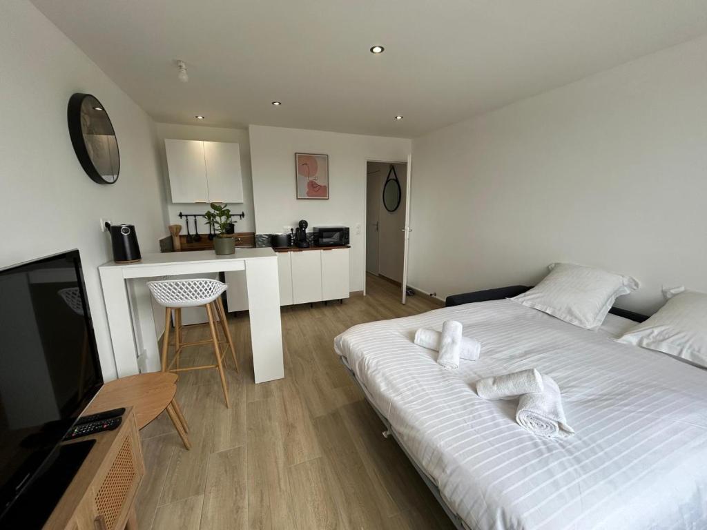 a bedroom with a white bed and a kitchen at Studio Siana in Chartres