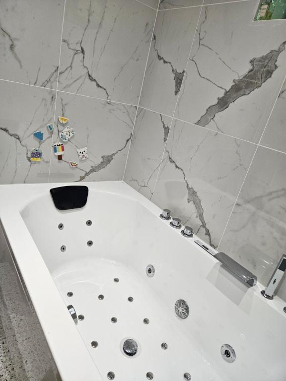 a white bath tub in a bathroom with marble walls at Casă de vacanță Chalet le Cristal in Sovata