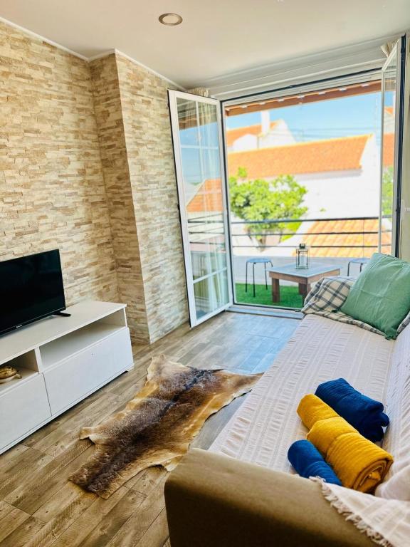 a living room with a couch and a large window at Sado Guest House in Alcácer do Sal