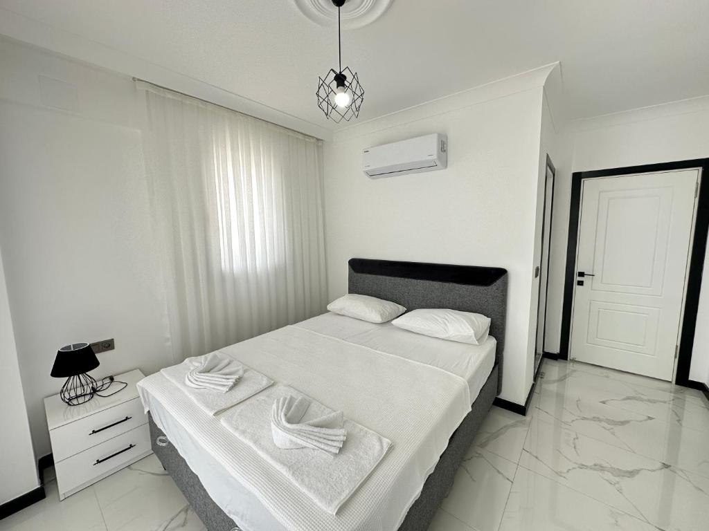 a white bedroom with a bed and a lamp at Dalyan villa star 1 in Ortaca