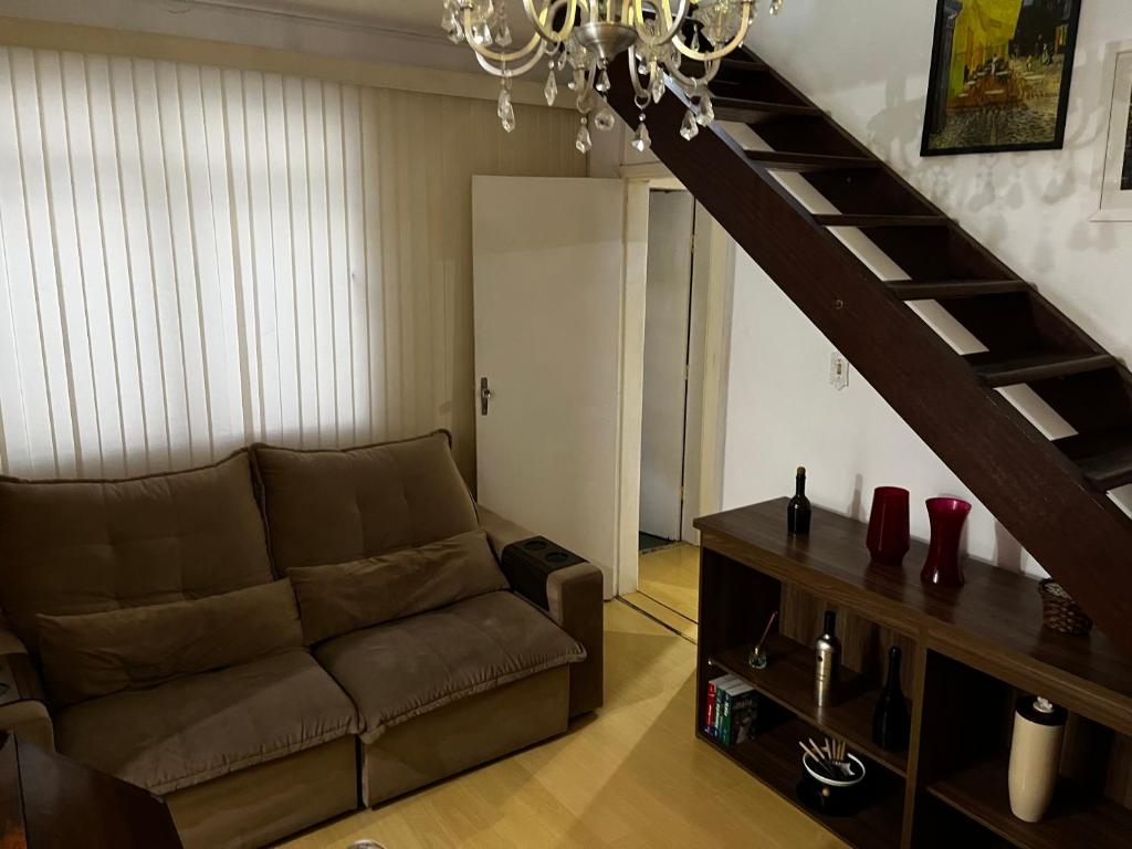 een woonkamer met een bank en een trap bij Apartamento Duplex Cobertura 5 min do centro in Juiz de Fora