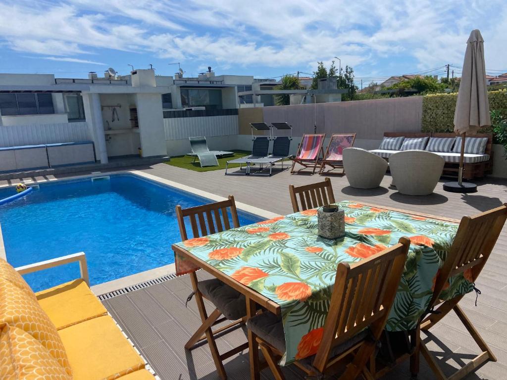 a patio with a table and chairs next to a pool at Meco Beach Villa in Sesimbra