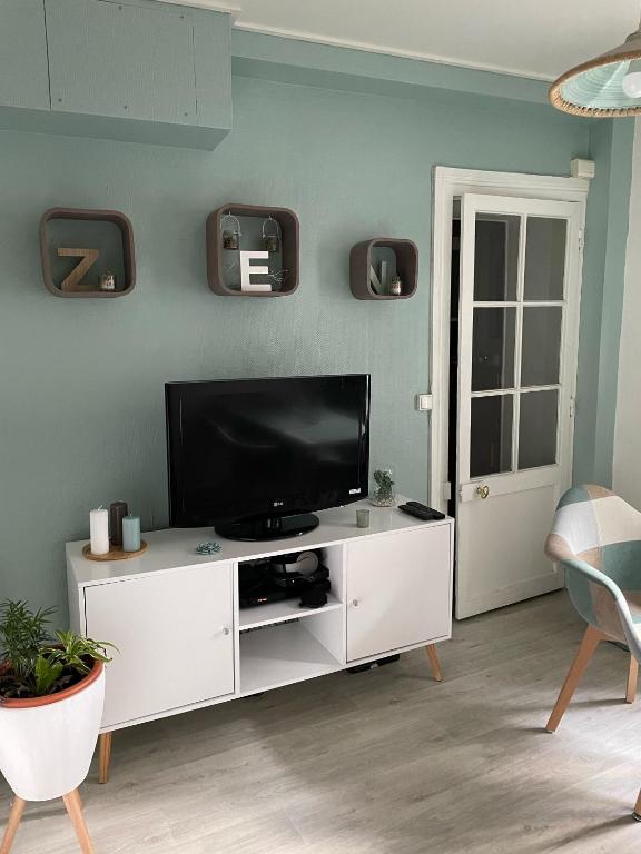 un salon avec une télévision sur un meuble blanc dans l'établissement Au bas de Montmartre !, à Paris