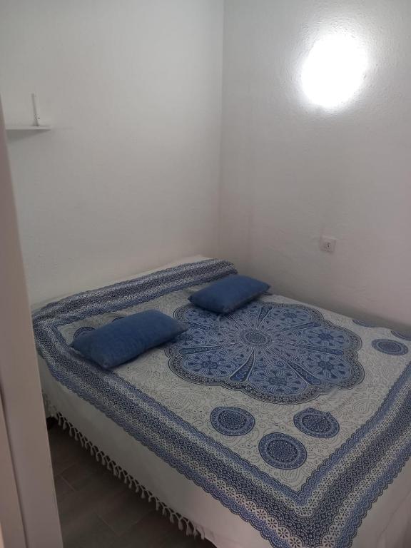 a bed with blue pillows on it in a room at Apartamento cerca del Mar in Empuriabrava