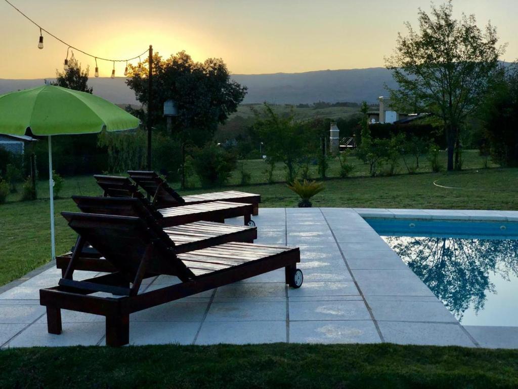 a group of chairs with an umbrella next to a pool at Cabaña Snowflakes in Villa Yacanto