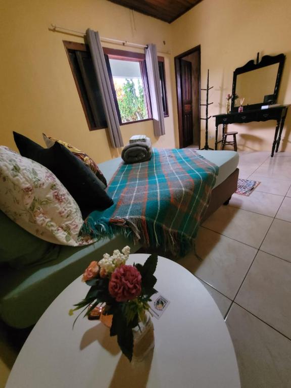 a living room with a couch and a table with flowers on it at Ecohostel Dos Canyons Santa Catarina in Praia Grande