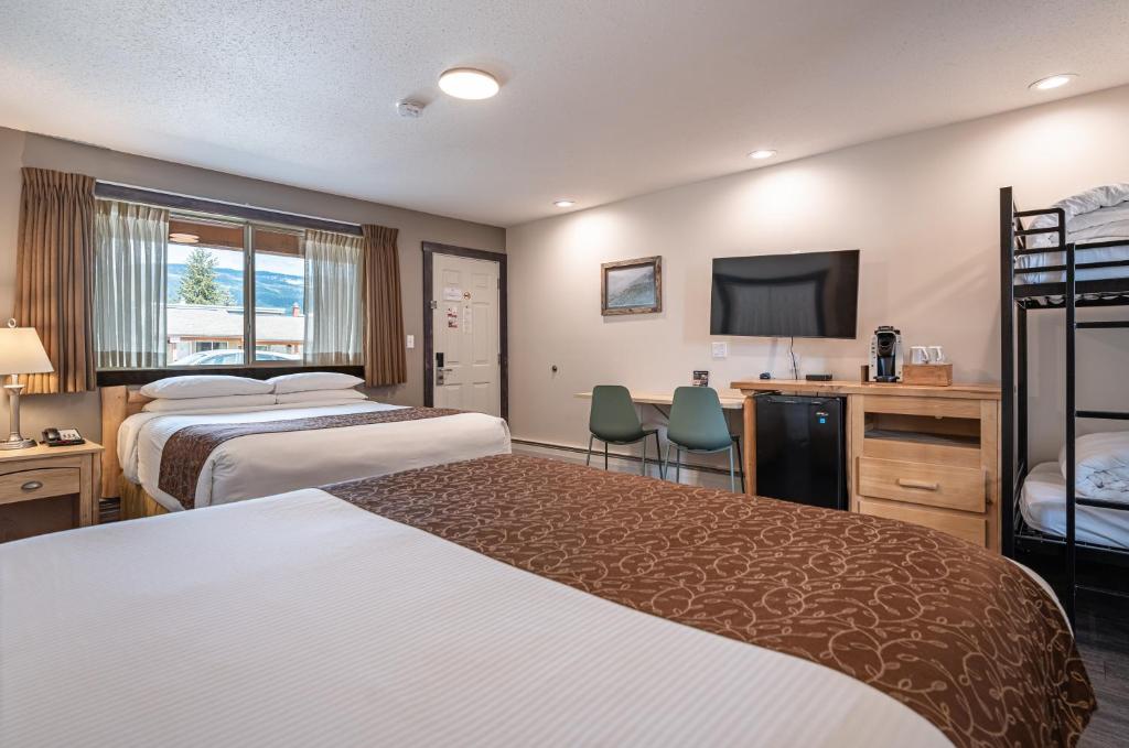 a hotel room with two beds and a flat screen tv at Swiss Chalet Motel in Revelstoke