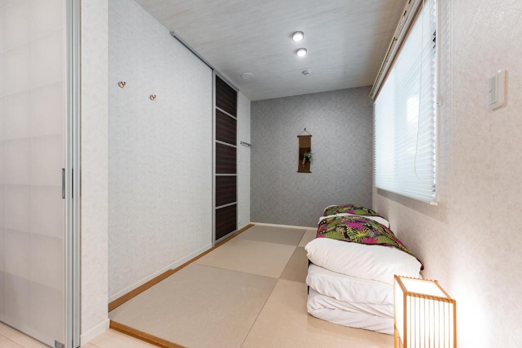 a hallway with a bed in a room with a window at リブレ芳斉 #102 in Housai