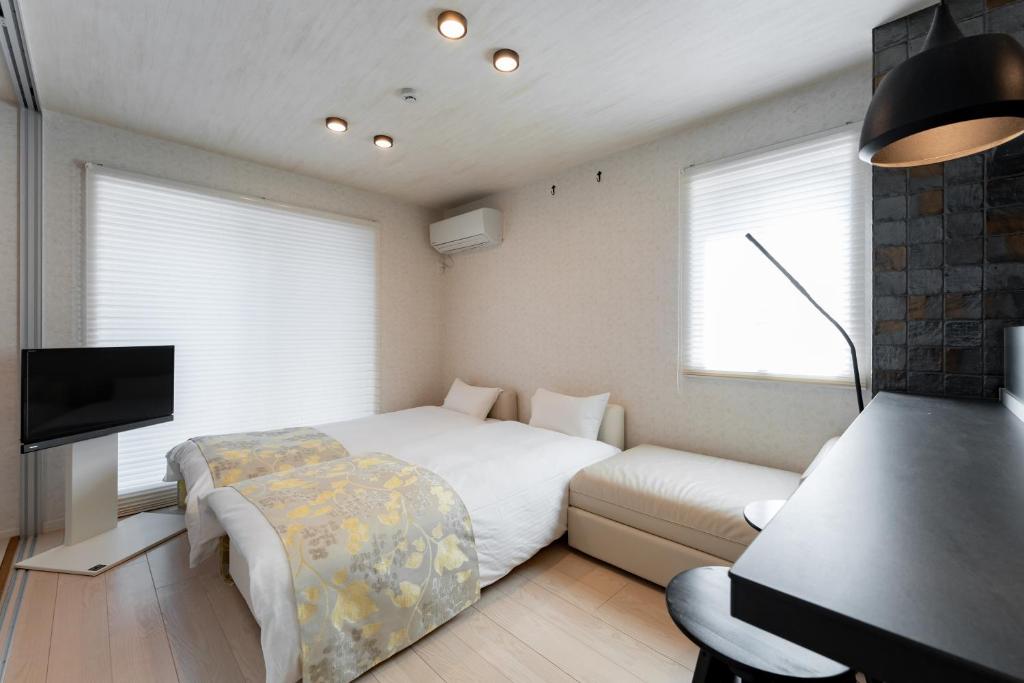 a bedroom with a bed and a couch and a tv at リブレ芳斉 #103 in Housai