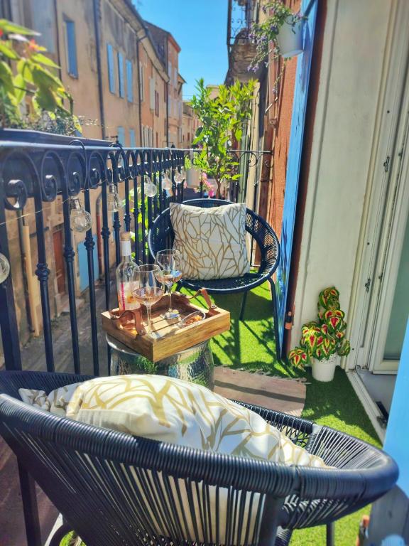 - un balcon avec une chaise et une table avec des verres à vin dans l'établissement L'appartement de la rivière qui chante, à Nyons