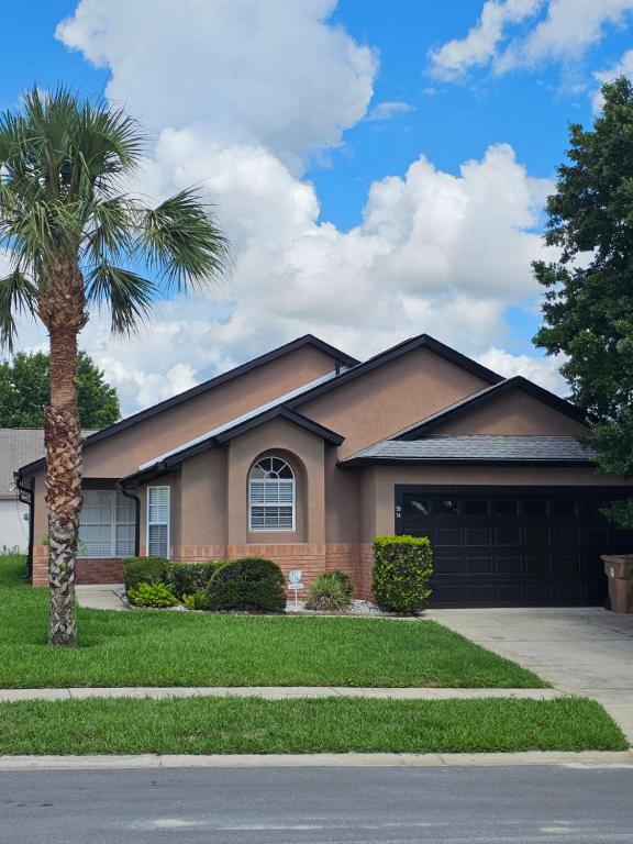 a house with a palm tree and a garage at Minnie Heaven in Kissimmee